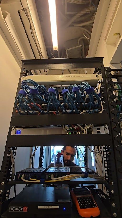Person working inside a server room with network cables and equipment racks.