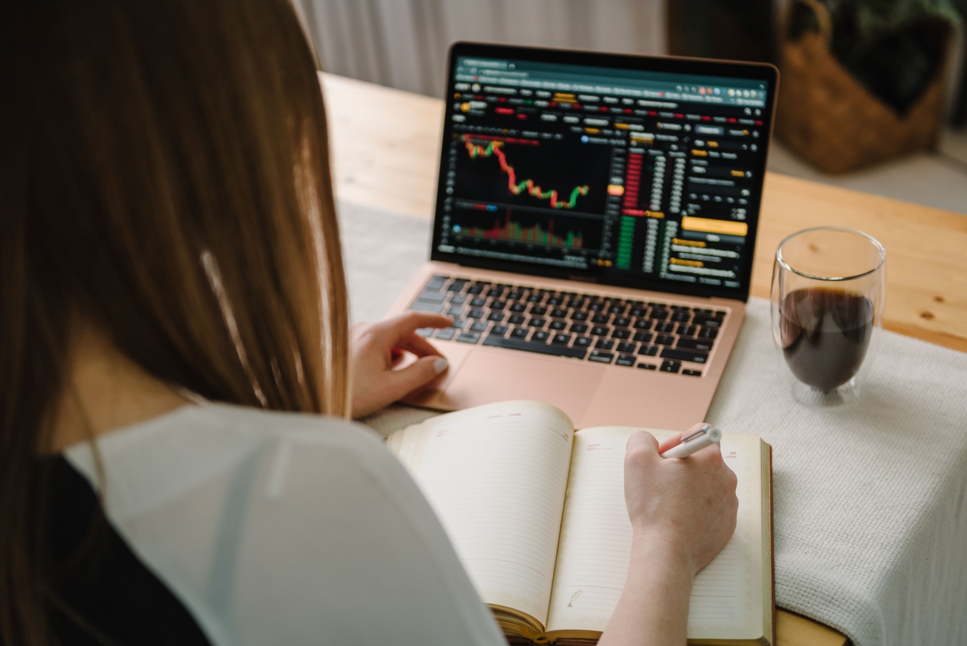 Tendencia del mercado alcista. Criptomoneda. Caída de las acciones de bitcoin. El gráfico muestra una fuerte caída en el precio de bitcoin. Vista superior trasera. La joven freelancer trabaja en una computadora portátil con gráficos, diagramas en pant